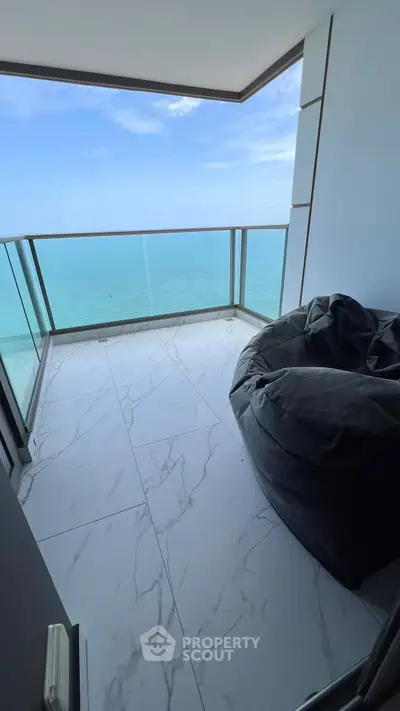 Stunning ocean view from a modern balcony with sleek glass railing and cozy seating.