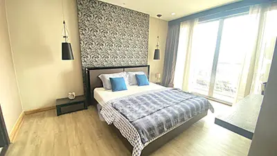 Spacious bedroom with modern decor and large windows offering natural light.
