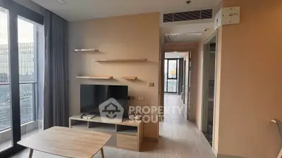 Modern living room with TV, wooden shelves, and large windows offering city views.