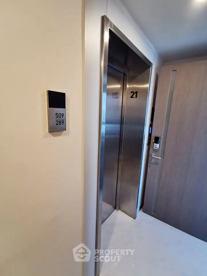 Modern elevator entrance in a sleek residential building with room number signage.