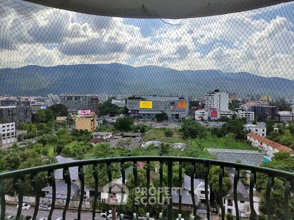 Stunning cityscape view from a high-rise balcony with lush greenery and mountains in the background.