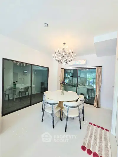 Elegant dining area with modern chandelier and glass doors leading to a bright room.