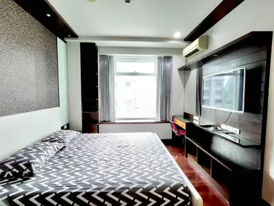 Modern bedroom with stylish decor, large window, and wall-mounted TV in a contemporary apartment.
