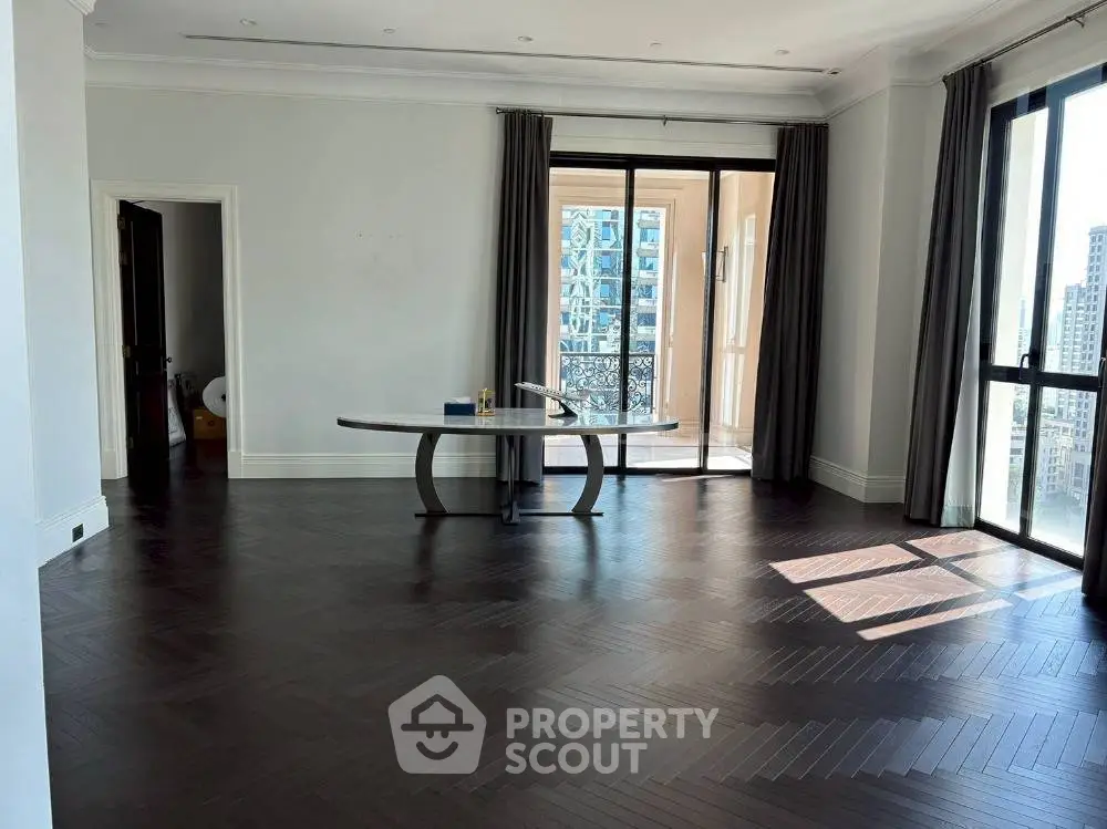Spacious living room with dark wood flooring and large windows in modern apartment.