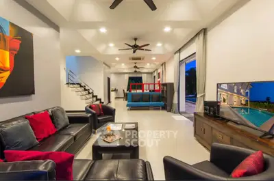 Luxurious modern living room with leather sofas, vibrant decor, and open layout leading to a scenic view.