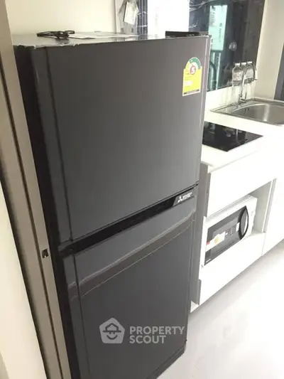 Modern kitchen with sleek black refrigerator and built-in microwave oven.