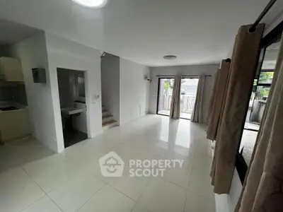 Spacious living room with large windows and balcony access, featuring modern tile flooring and neutral decor.
