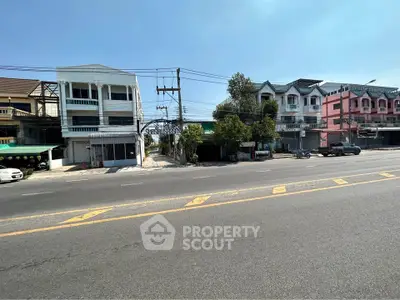 Street view of residential buildings with clear sky and road in front, showcasing urban living.