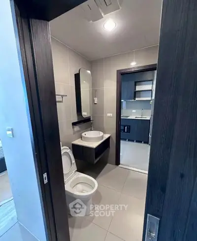 Modern bathroom with sleek fixtures and open view to adjacent kitchen area.