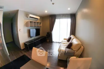 Modern living room with cozy sofa, wall-mounted TV, and natural light from large window.