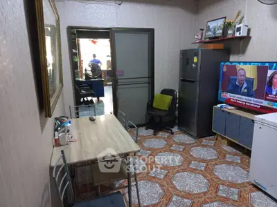 Cozy living room with dining table, fridge, and TV, featuring patterned tile flooring and modern decor.