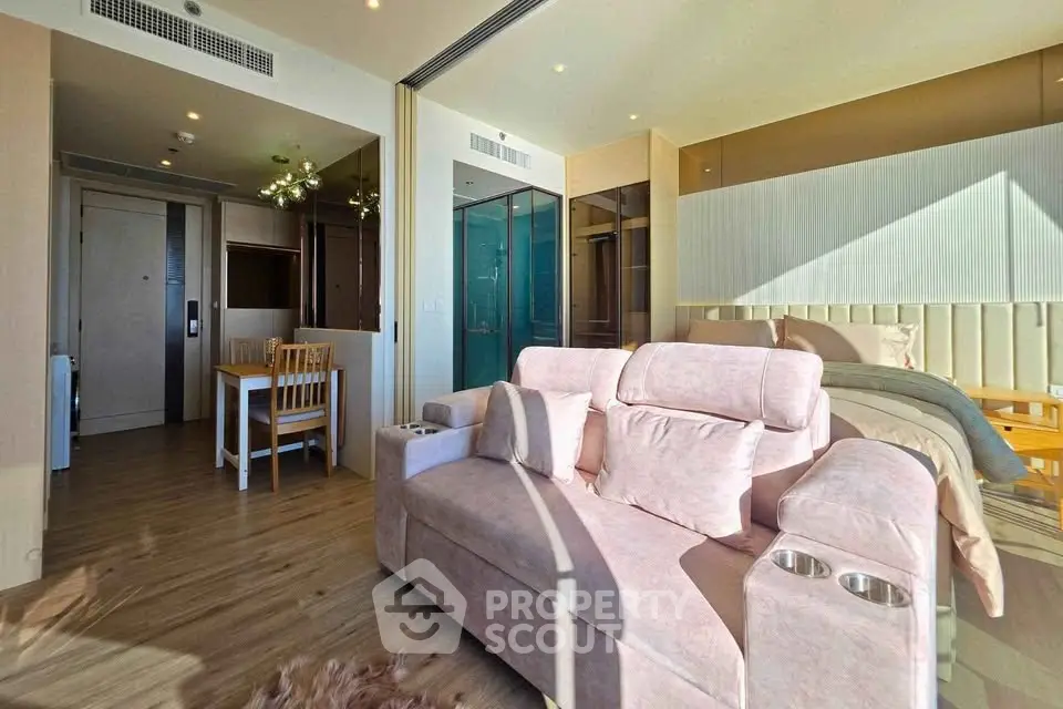 Luxurious open-plan living room with plush pink sofa and elegant dining area, bathed in natural light.