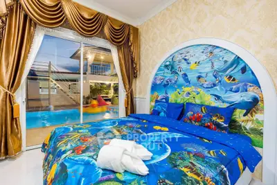 Vibrant bedroom with ocean-themed decor and pool view, featuring luxurious drapes and sliding glass doors.