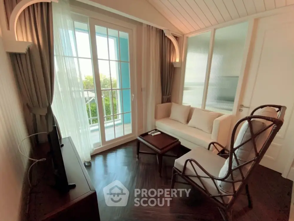 Charming living room with elegant decor and natural light, featuring a cozy seating area and large windows.