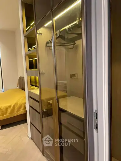 Modern bedroom with sleek glass wardrobe and cozy bed in stylish apartment.