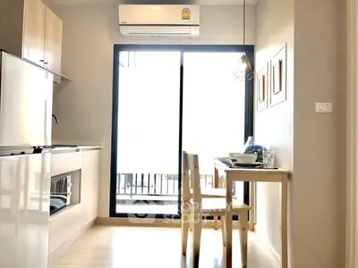 Modern kitchen with open layout and dining area, featuring sleek appliances and natural light.