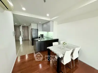 Modern open-layout kitchen and dining area with sleek design and wooden flooring.