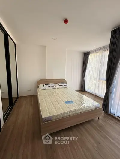 Spacious bedroom with large windows and wooden flooring in modern apartment