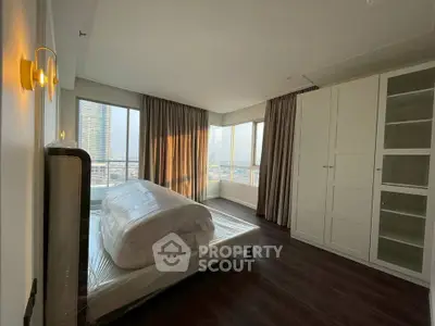 Spacious bedroom with large windows and city view in modern apartment