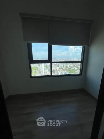 Spacious room with large window offering stunning cityscape views, perfect for urban living.