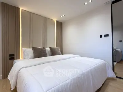 Modern bedroom with elegant lighting and cozy bedding in a stylish apartment.
