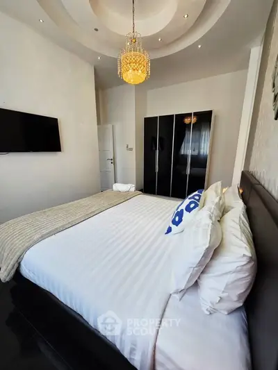 Luxurious bedroom with elegant chandelier and modern decor in a stylish apartment.