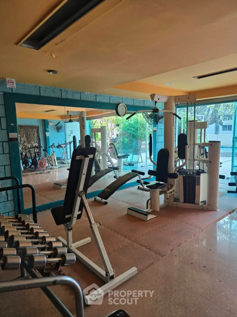 Spacious gym with modern fitness equipment and large windows for natural light.