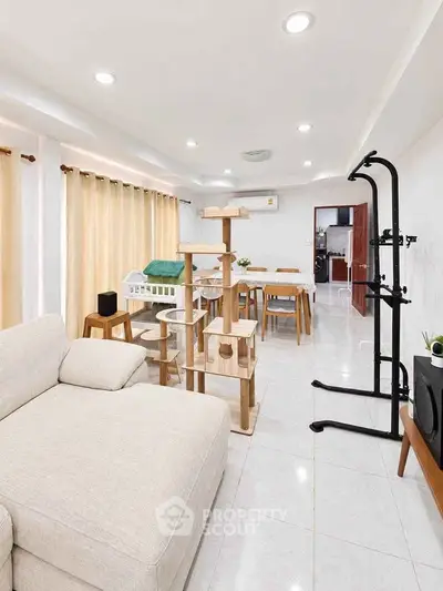 Spacious living room with modern furniture and cat tree, perfect for pet lovers.