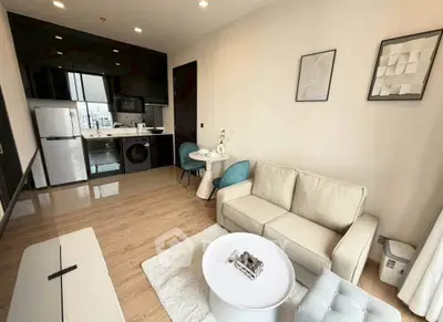 Modern living room with open kitchen, featuring sleek appliances and stylish decor.