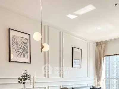 Elegant living room with modern lighting and framed art, featuring a cozy ambiance and natural light.