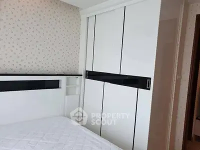 Cozy bedroom with modern white wardrobe and floral wallpaper, perfect for a serene living space.