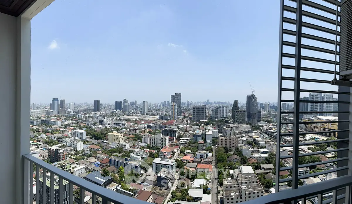 Stunning cityscape view from a high-rise balcony showcasing urban skyline and clear blue sky.