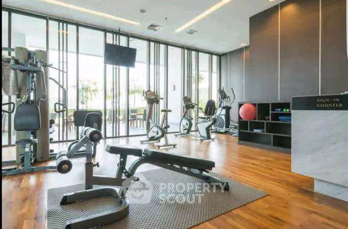 Modern gym with state-of-the-art equipment and wooden flooring in luxury apartment building.