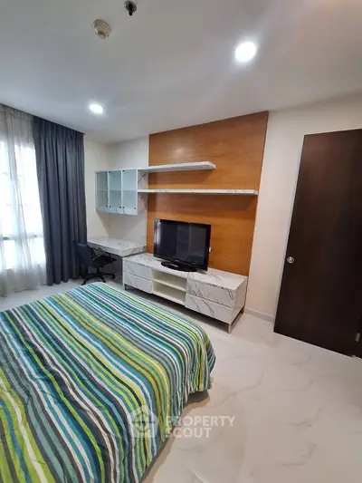 Modern bedroom with stylish decor and built-in TV unit, perfect for comfortable living.