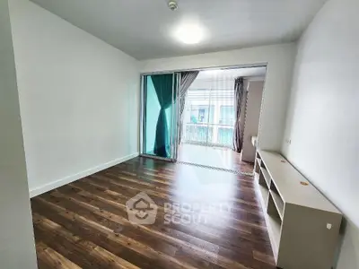 Spacious living room with wooden flooring and large windows for natural light.