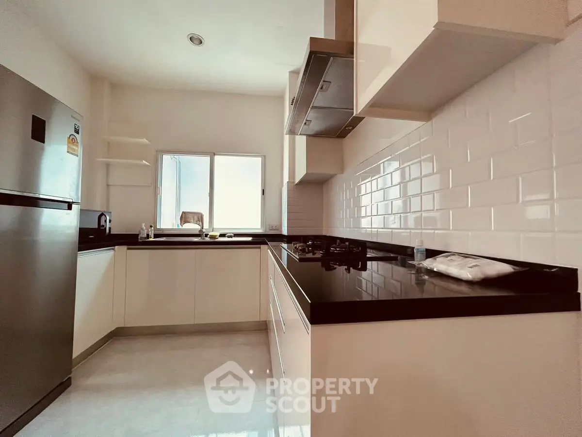 Modern kitchen with sleek black countertops and stainless steel appliances.