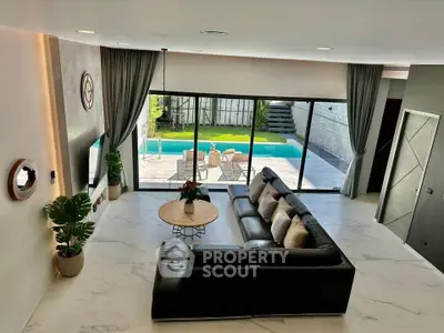 Luxurious living room with modern decor and pool view, featuring a spacious leather sofa and elegant marble flooring.