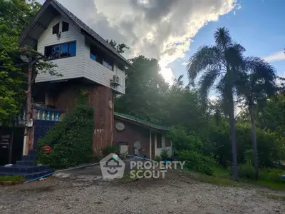 Charming rustic house surrounded by lush greenery and palm trees, offering a serene natural retreat.