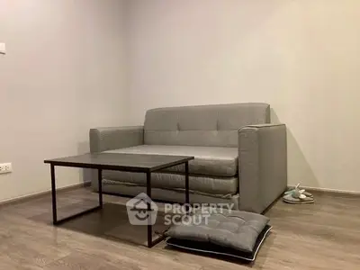 Minimalist living room with gray sofa and modern coffee table on wooden floor.