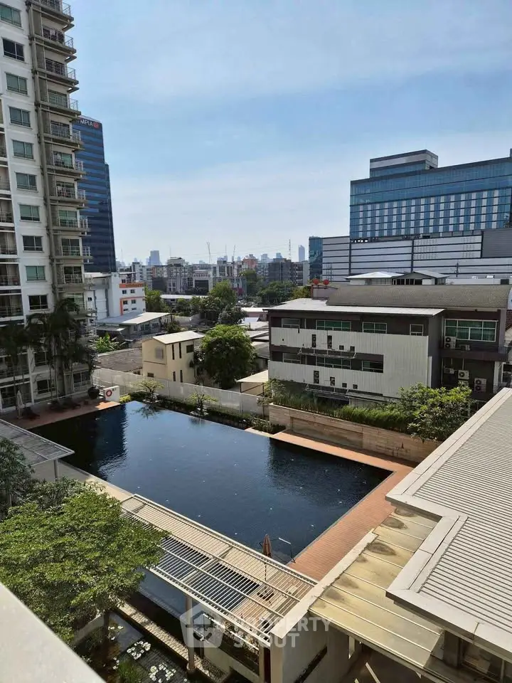 Stunning cityscape view from a high-rise apartment overlooking a serene pool and modern buildings.