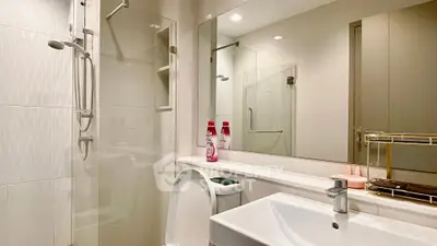Modern bathroom with sleek fixtures and glass shower enclosure.