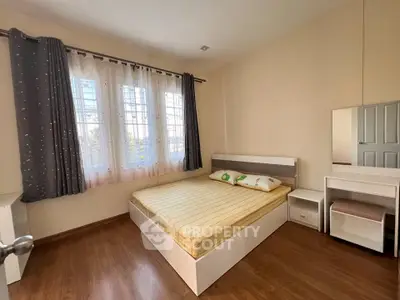 Cozy bedroom with wooden flooring and ample natural light from large windows.