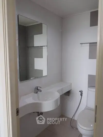 Modern bathroom with sleek fixtures and minimalist design, featuring a wall-mounted sink and toilet.