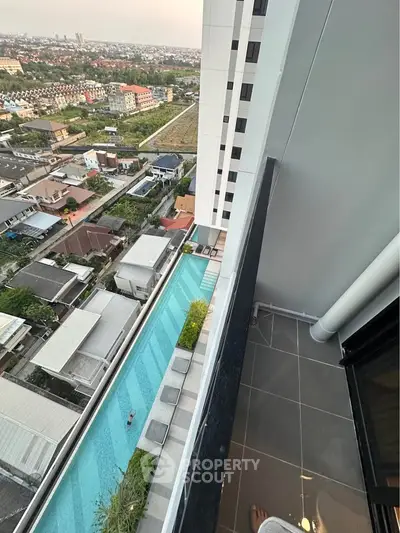 Stunning high-rise balcony view overlooking cityscape and luxurious pool, perfect for urban living.