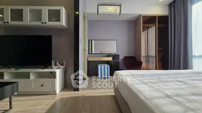 Modern bedroom with TV and air conditioning, featuring a stylish open wardrobe and natural light.