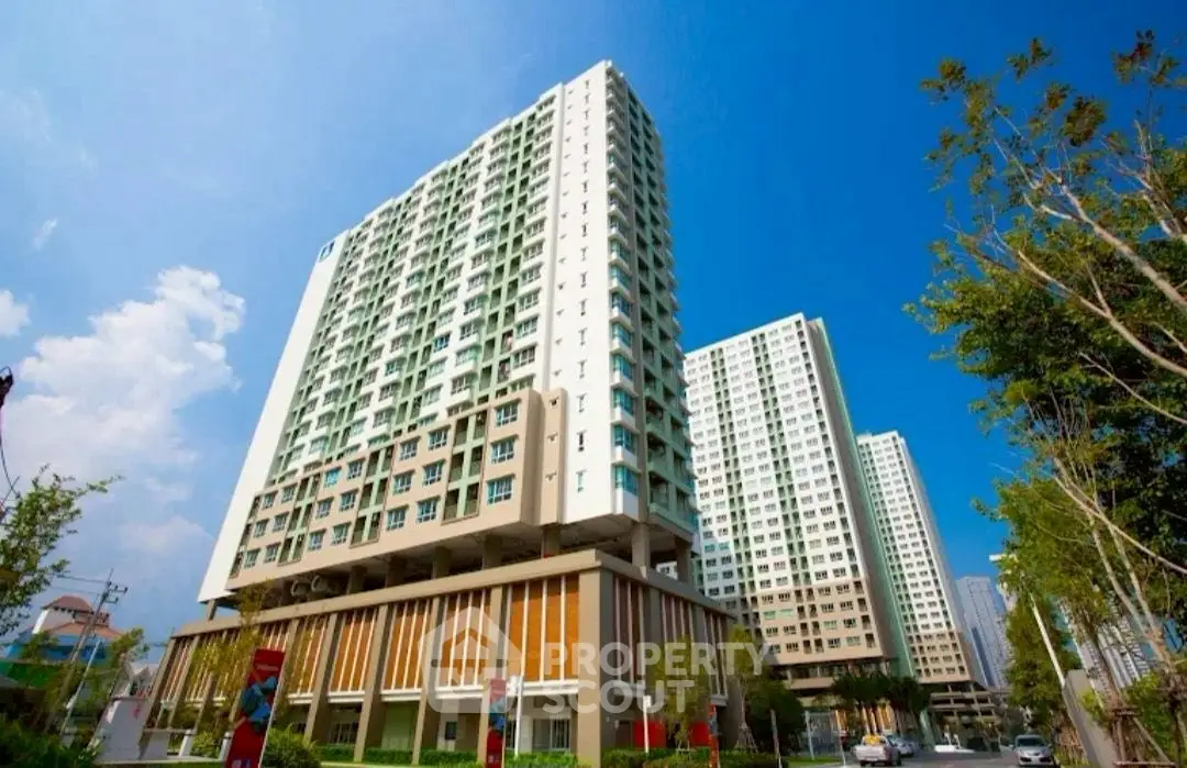 Modern high-rise residential buildings with clear blue sky and lush greenery.