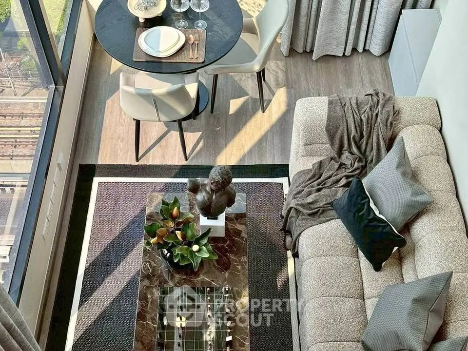 Modern living room with stylish decor and large windows offering natural light and city views.