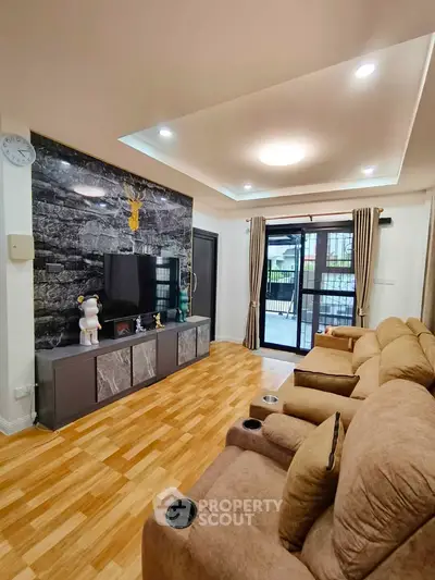 Spacious living room with modern decor and large windows opening to a balcony.