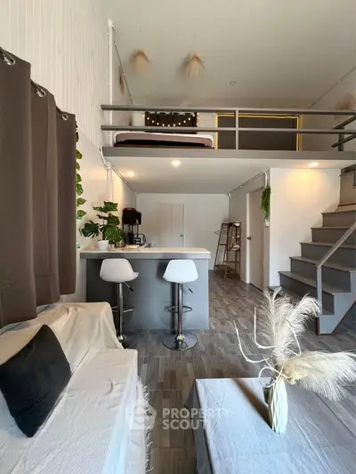 Modern loft apartment with stylish decor and mezzanine bedroom, featuring open living space and sleek kitchen.