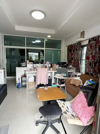 Cozy living room with eclectic decor and ample natural light.